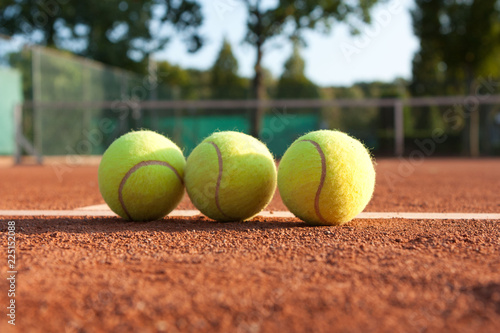 Three tennis balls on court.