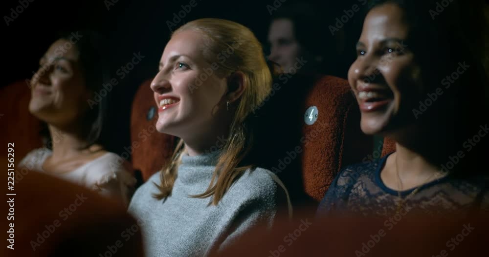 Happy, smiling woman sitting in a busy movie theatre enjoying a funny moment in the movie. Happy, smiling woman sitting in a busy movie theatre enjoying a funny moment in the movie.