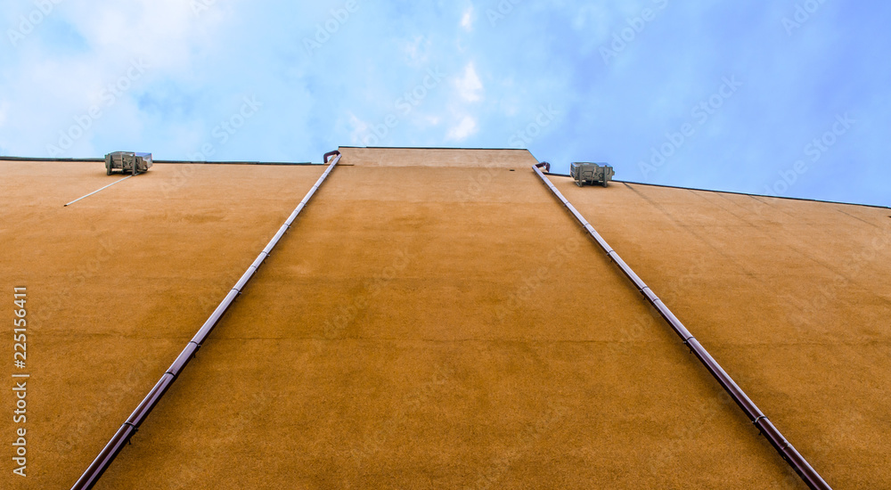 An abstract view of a building wall with blue sky and white clouds