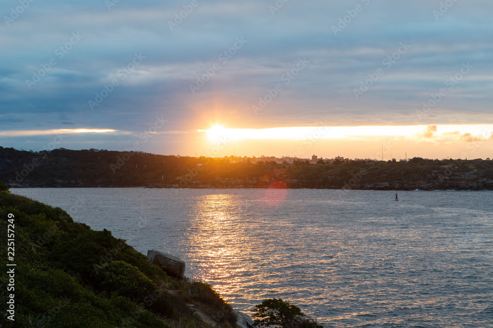 Sunset light through a gap in the clouds at Sydney Harbour.