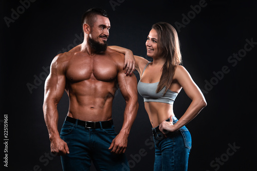 Fitness couple on a black background looking each other and smiling