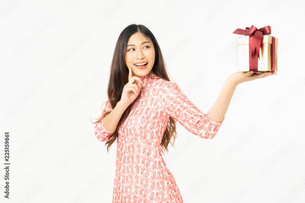 Photo of asian curious woman in red dress rejoicing her birthday or new year gift box. Young woman holding gift box with red bow being excited and surprised holiday present isolated white background Photo of asian curious woman in red dress rejoicing her birthday or new year gift box. Young woman holding gift box with red bow being excited and surprised holiday present isolated white background
