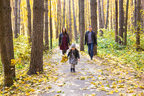 People  family and leisure concept - mixed race father and mother have fun in autumn park with their daughter