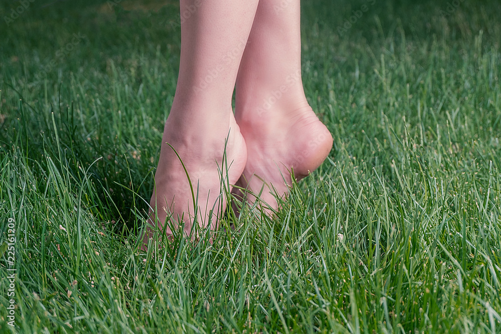Girl standing in green grass on toes backlit, harmony and carefree concept