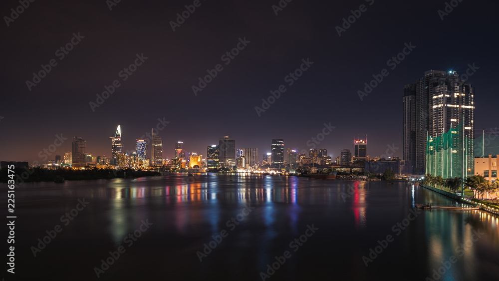 Urban night skyline panoramic view of Ho Chi Minh city. Front view on colored skyscrapers in downtown from the river