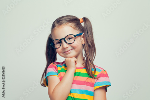 beautiful cute little girl posing and smiling to camera with her hand under chin