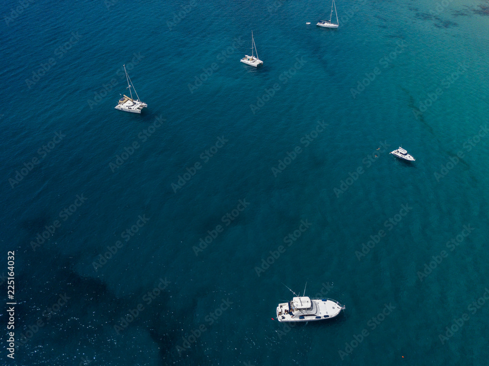 Vista aerea di barche ormeggiate che galleggiano su un mare trasparente. Immersioni relax e vacanze estive. Costa delle Canarie, Lanzarote. Spagna
