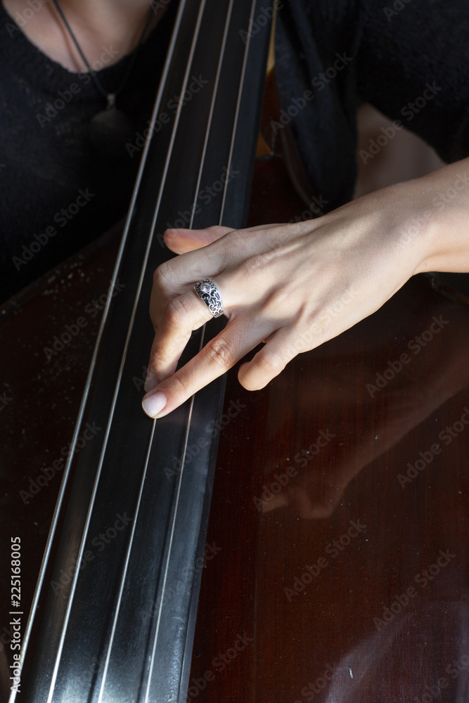 Hands of a musician playing on a contrabass closeup Hands of a musician playing on a contrabass closeup