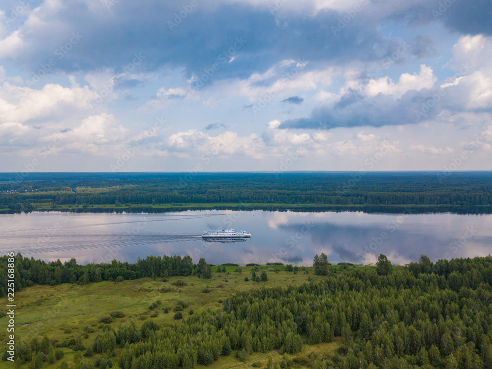 Aerial view of river Volga and cruise ship sailing along. Green riversides and meadows. Summer photo from drone, Russia