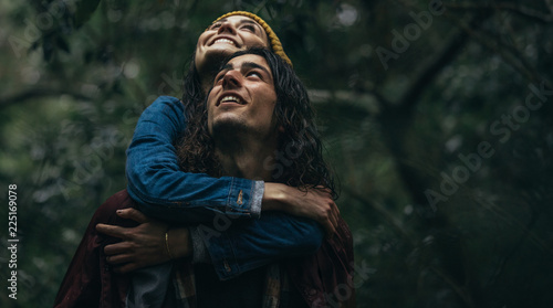 Couple at forest piggybacking in rain