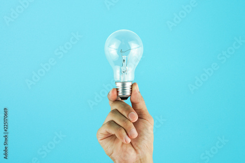 Hand holding light bulb on blue background. Concept for new ideas with innovation and creativity.
