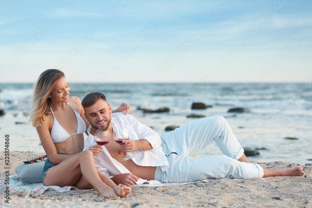 Young couple with glasses of wine on beach Young couple with glasses of wine on beach