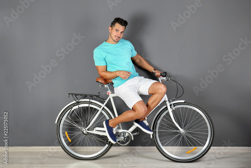 Handsome young hipster man with bicycle near color wall
