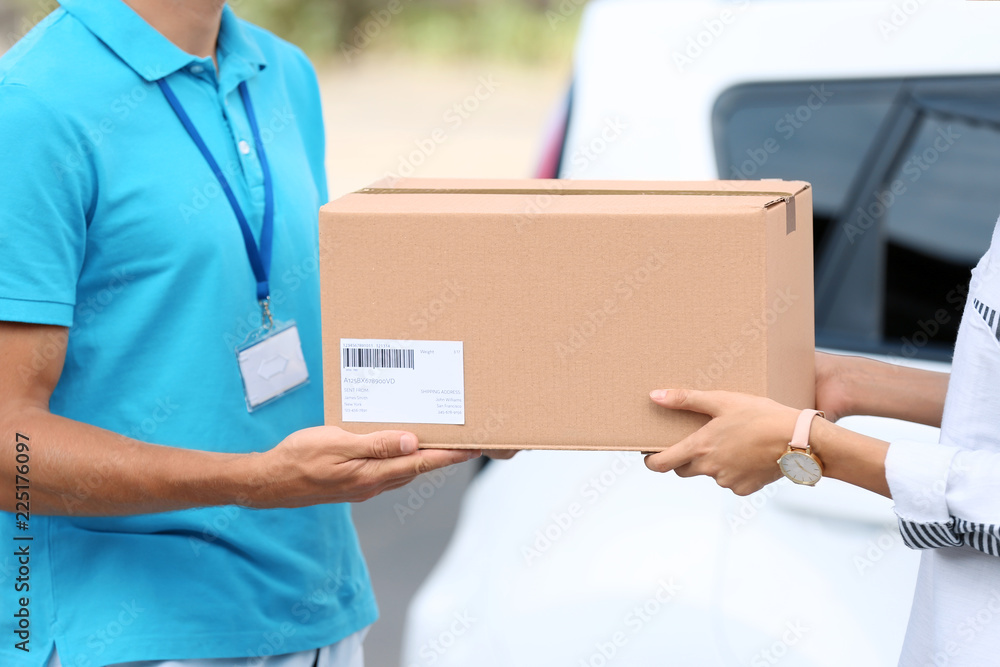 Young woman receiving parcel from courier outdoors Young woman receiving parcel from courier outdoors