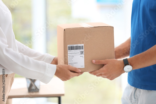 Bild auf Leinwand Young woman receiving parcel from courier in office