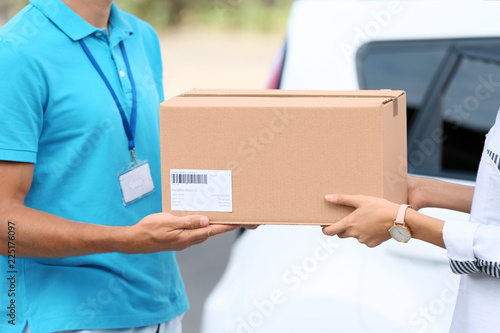 Young woman receiving parcel from courier outdoors © New Africa
