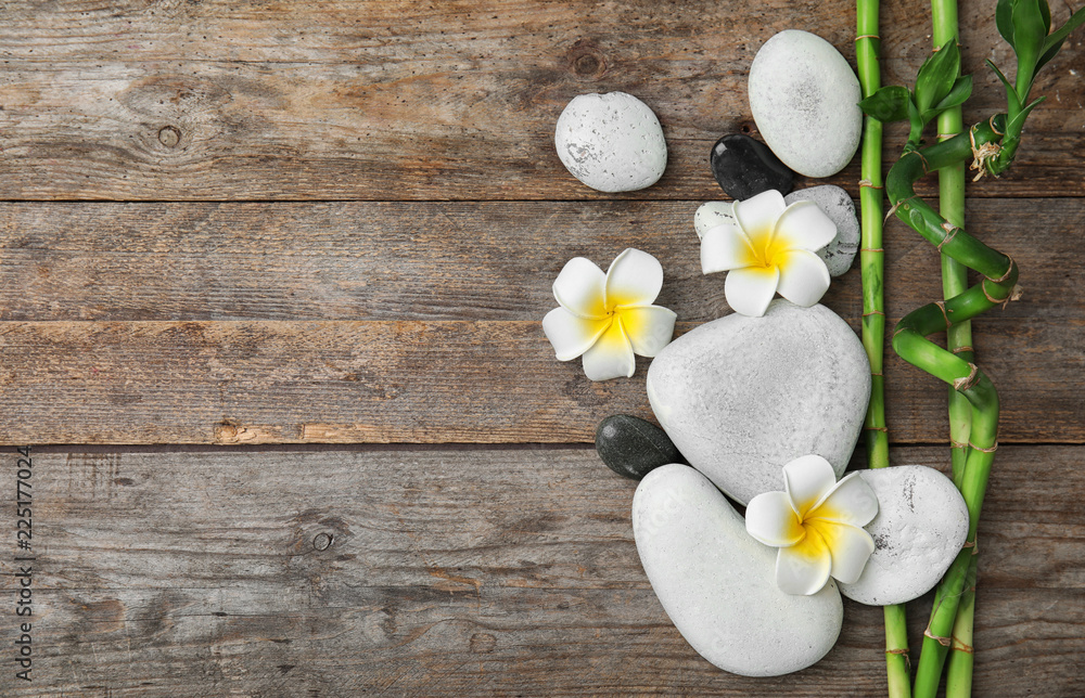 Flat lay composition with bamboo branches and spa stones on wooden background. Space for text Flat lay composition with bamboo branches and spa stones on wooden background. Space for text