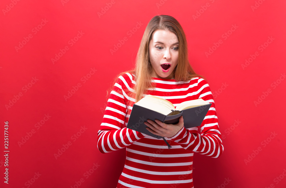 Young woman with a book on a red background Young woman with a book on a red background