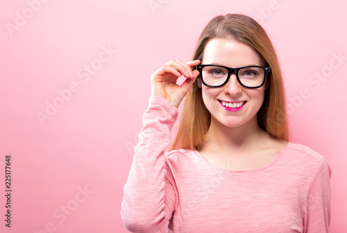 Young woman with eye glasses on a pink background