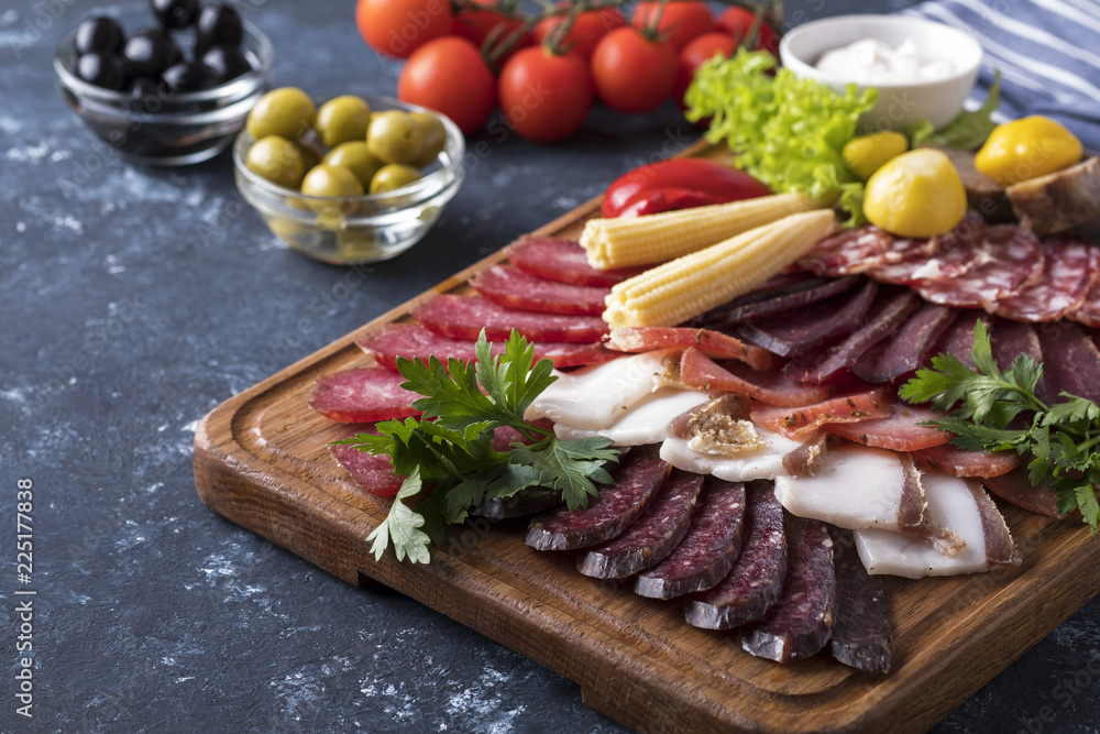 Different sausages with pickled vegetables. Sliced salami on wooden board Different sausages with pickled vegetables. Sliced salami on wooden board