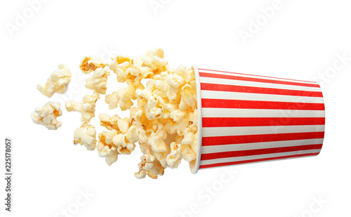 Overturned cup with delicious fresh popcorn on white background, top view