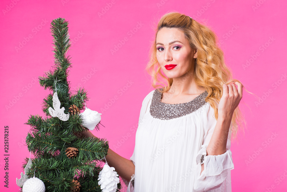Young happy woman near christmas tree on pink background Young happy woman near christmas tree on pink background