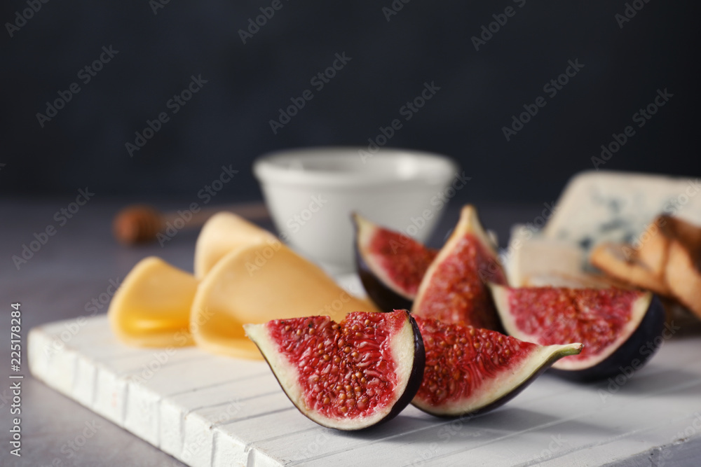 Wooden board with ripe fig slices on grey table, closeup Wooden board with ripe fig slices on grey table, closeup