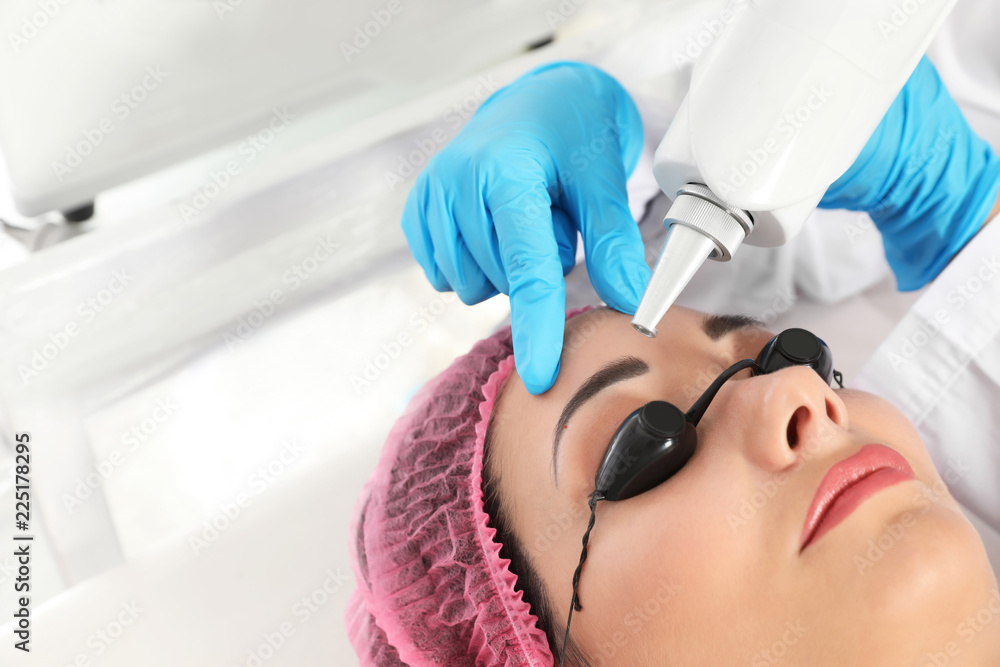 Naklejka premium Woman undergoing laser tattoo removal procedure in salon, closeup