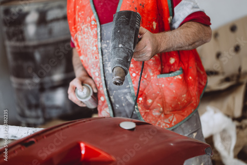 Foto Car detailing - Man with sandpaper in auto repair shop sanding polishing and preparing car parts for painting
