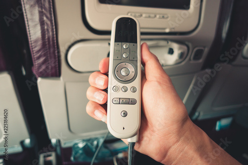 Close-Up of Male Hand is Holding Remote Electronic Device Entertainment Multimedia Control on Air Flight, Airplane Facility Service on Passenger Seat. Monitor Control inside Passengers Cabin Aircraft