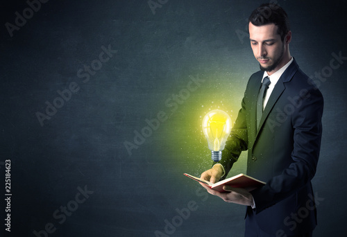 Businessman holding book with bulb.