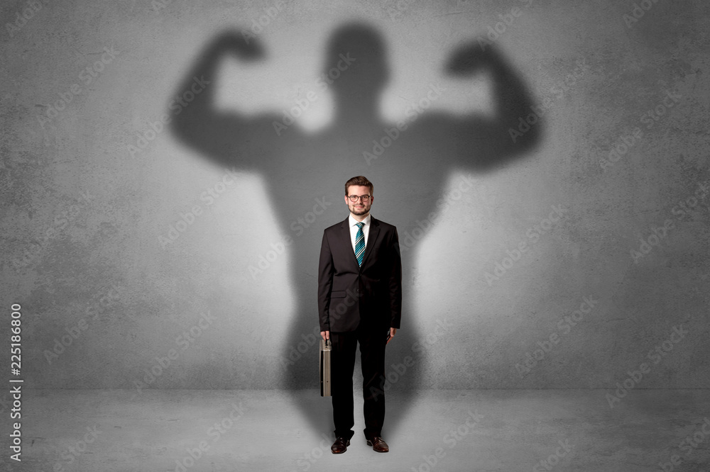 Obraz premium Lovely serious businessman standing with a muscular powerful shadow behind his back 