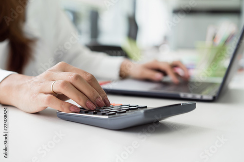 female accountant using calculator and typing on laptop. finance accounting plan concept