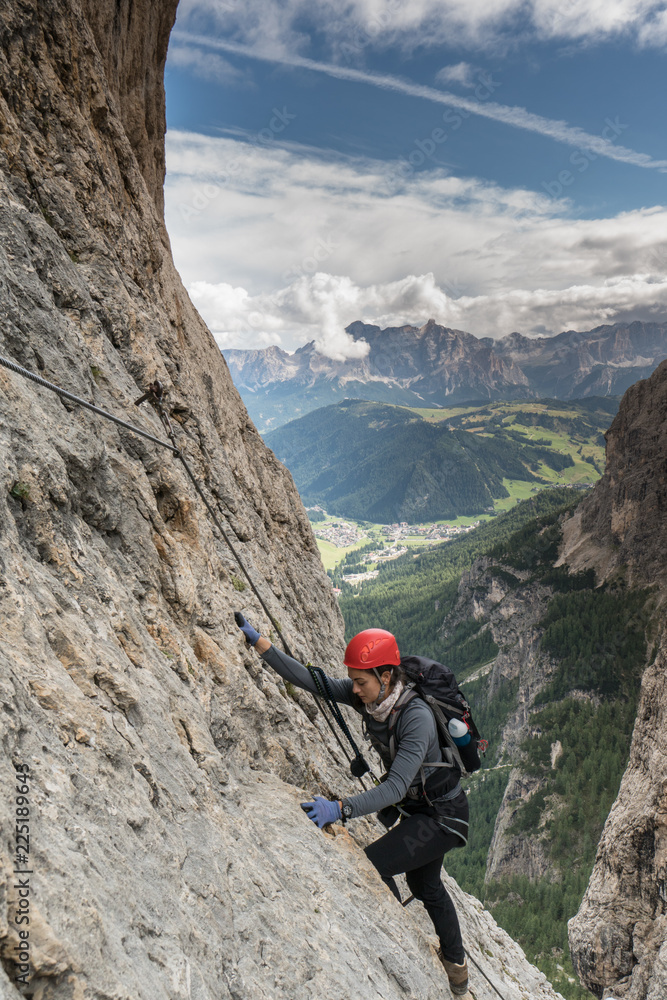 young pretty female mountain climber on a Via Ferrata in the Dolomites in Alta Badia