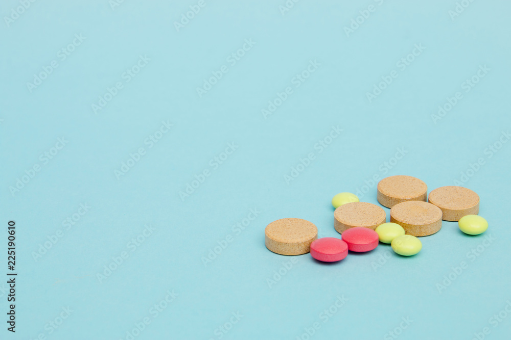 Different medicines tablets on blue background selective focus, copy space
