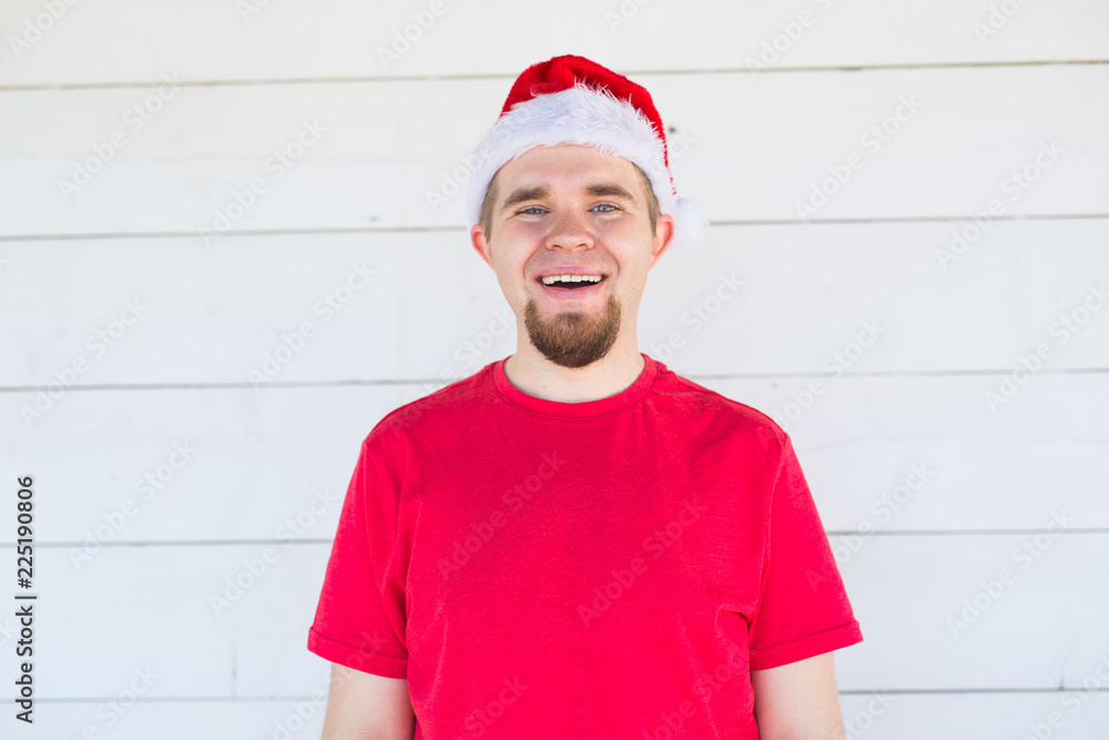 Christmas, holidays, people concept - young funny man in santa hat and shirt smiling over the white background Christmas, holidays, people concept - young funny man in santa hat and shirt smiling over the white background
