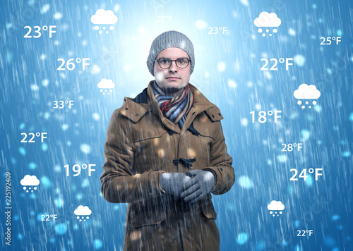 Young man freezing in warm clothing with weather condition and forecast concept
