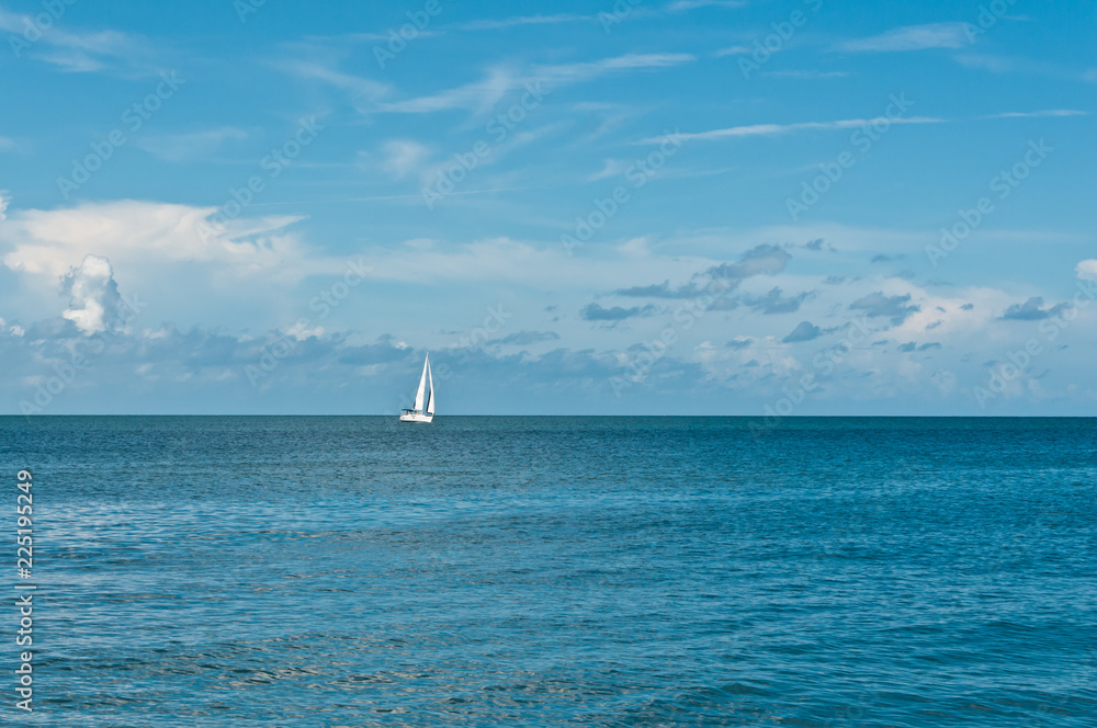 Front view, long distance of a sailing vessel  underway on a stiff breeze toward the horizon on tropical, autumn,  sunny day on the Gulf of Mexico