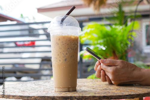 Business woman holding cold coffee and smartphone checking data of her work from outdoor.