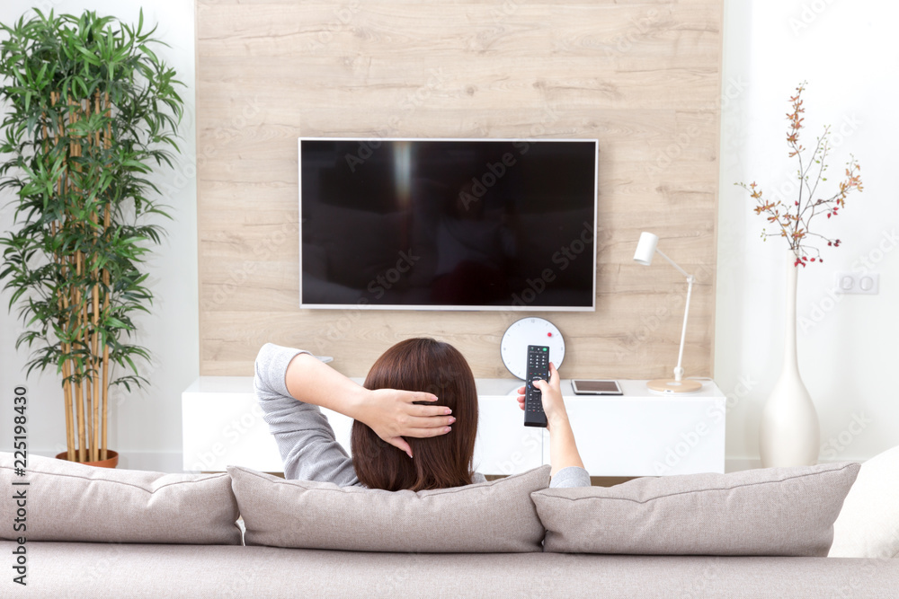 Fototapeta Młoda kobieta ogląda TV w pokoju