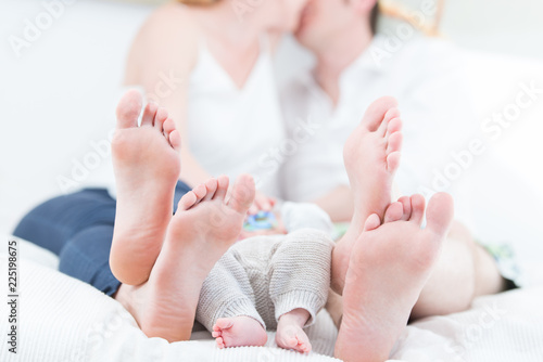 Junge Eltern mit Ihrem Baby im Bett küssen sich photo