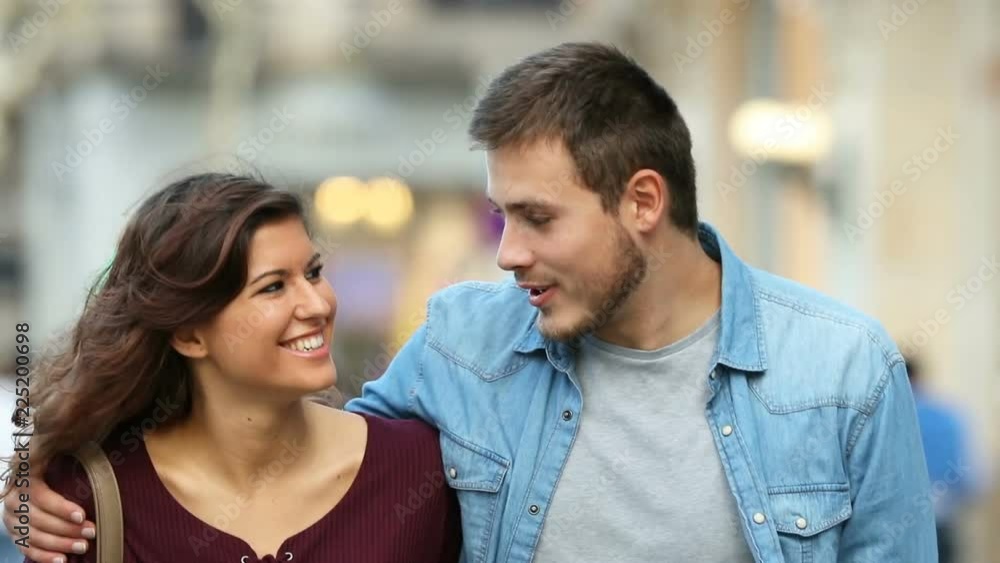 Front view of a happy couple talking and walking towards camera Front view of a happy couple talking and walking towards camera
