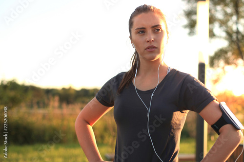 Fototapeta Naklejka Na Ścianę i Meble -  Young attractive sporty fitness woman standing outdoors at sunset or sunrise in city.