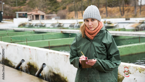 Photography Female worker of fish farm writing something in notebook