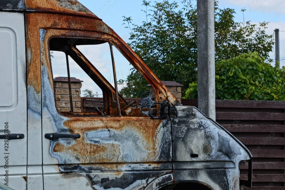part of the cab of a burnt white car in the street