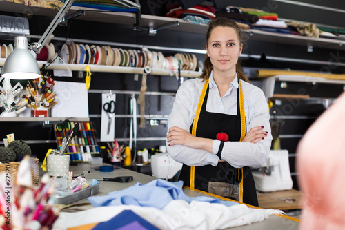 Portrait of woman designer who is standing on her workplace in time designing new collection