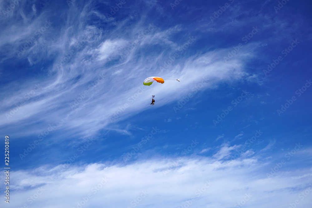 Lighty color tandem parachute against the background of great clouds and silhouettes of skydivers Lighty color tandem parachute against the background of great clouds and silhouettes of skydivers