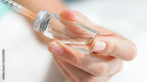 Macro image of female nurse preparing syringe for injection