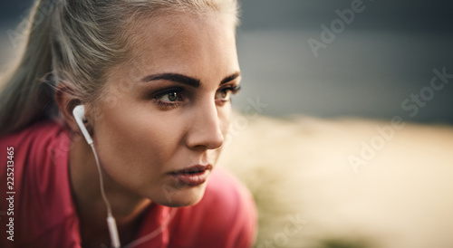 Closeup of female runner wearing earphones looking away