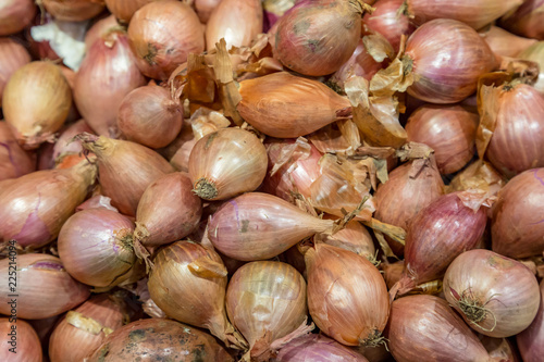 A full frame photograph of a pile of shallots onions on a market stall
